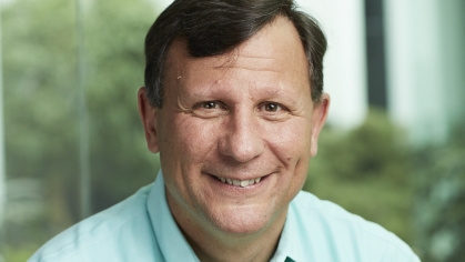 Headshot of white male with brown hair wearing a light green collared shirt.