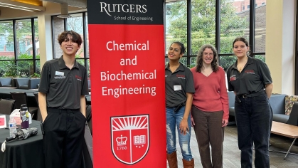 one male and three females standing next to a red and black Rutgers Chemical and Biochemical Engineering retractable banner