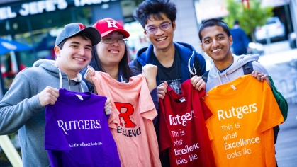 four students show off Rutgers What Excellence Looks Like t-shirts in a variety of colors
