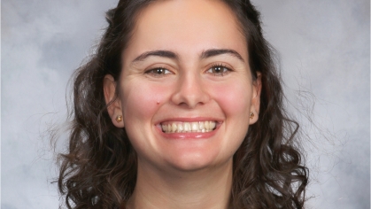 Headshot of female with shoulder length curly brown hair.