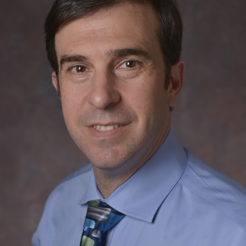 headshot of male wearing a blue shirt and tie