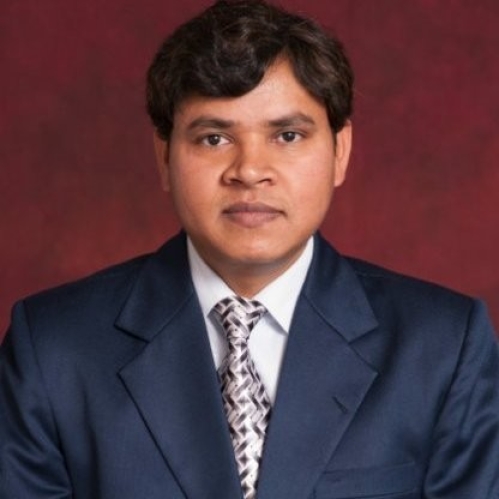 Head shot of Indian man with short dark brown hair, wearing a blue suit, white shirt, and patterned tie.