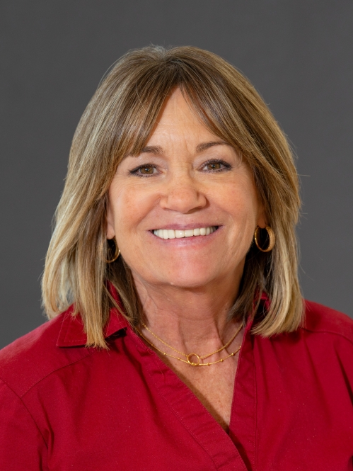 Headshot of woman with shoulder length light brown hair wearing a red button down shirt.