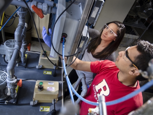 one female and one male student wearing goggles looking at equipment in a chemical engineering lab