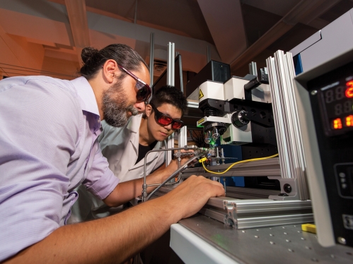 male professor wearing goggles and male student working in chemical engineering lab