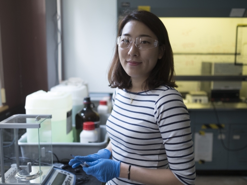 female student wearing stripped shirt in lab wearing goggles 