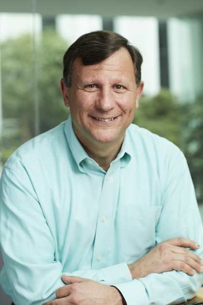 Headshot of white male with brown hair wearing a light green collared shirt.