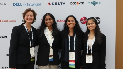 Four smiling young women wearing conference identification badges.