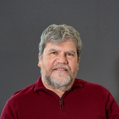Headshot of male with a beard and moustache wearing a maroon zip pullover.