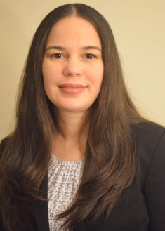 head shot of woman with long brown hair wearing a black suit jacket and patterned blouse
